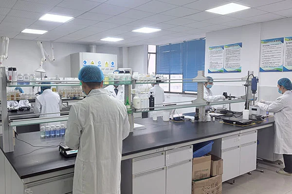 Scientists wearing lab coats and hairnets working in a well-equipped laboratory with workstations and scientific tools.